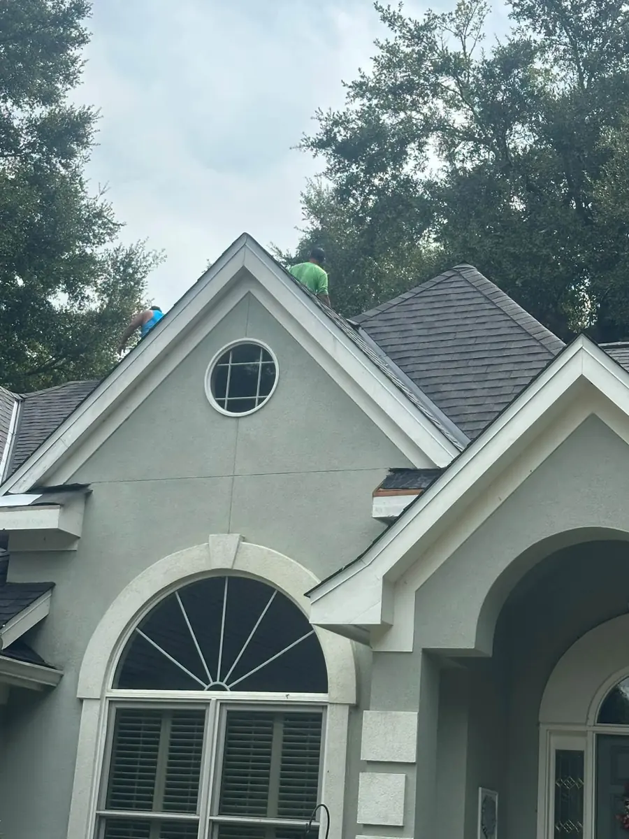 Sage stucco home with arched window and new roof