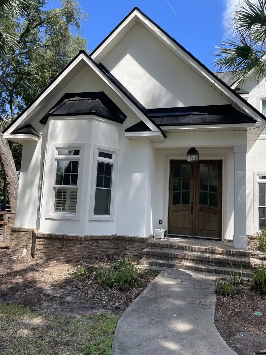 White coastal home with black metal accent roofs